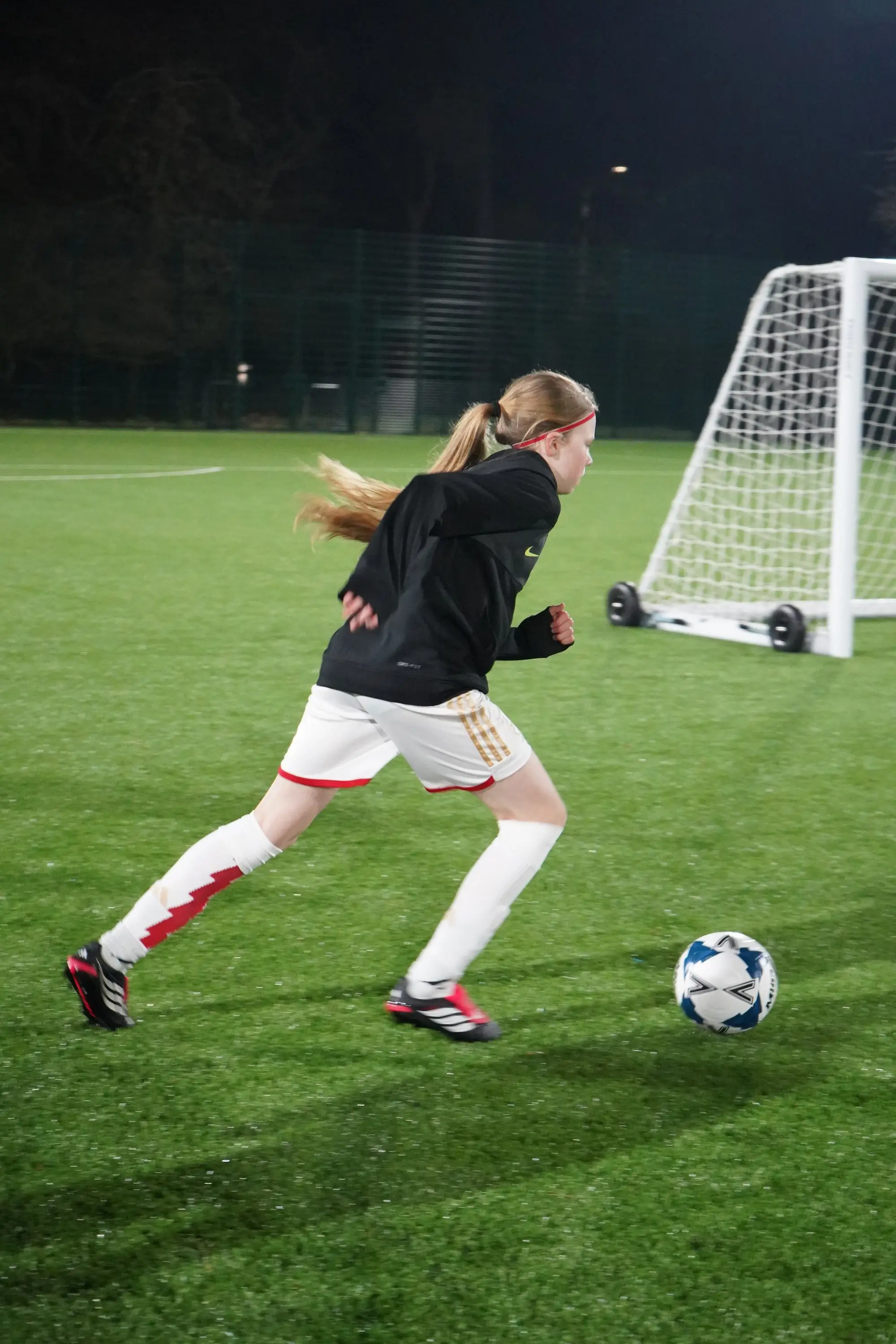 A player driving at goal during a floodlit TouchTight training session